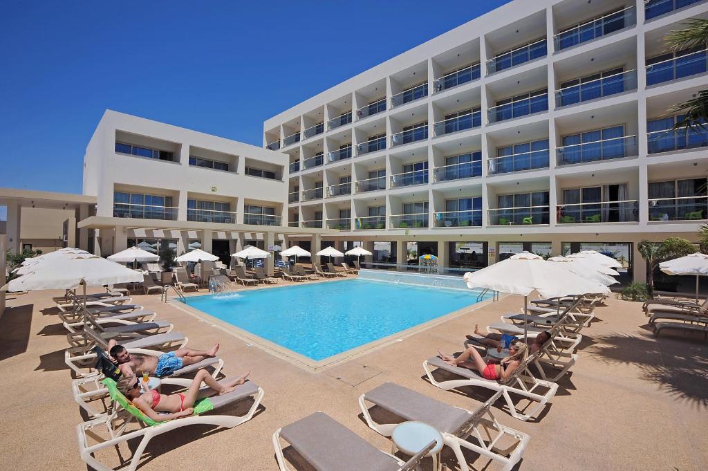 un grupo de personas sentadas en sillas junto a una piscina en Nelia Gardens, en Ayia Napa