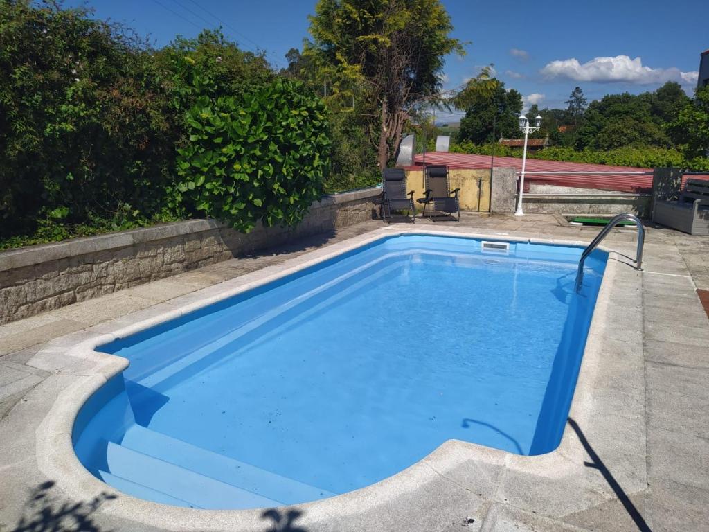 a swimming pool with blue water in a yard at Apartamento con jardín y piscina temporada verano privados in Samieira