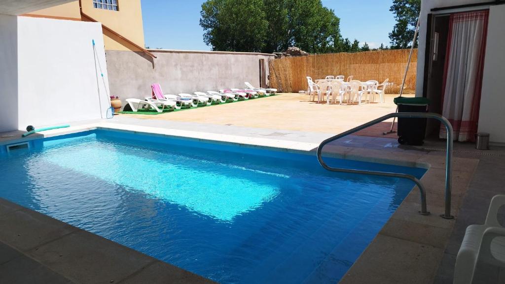 a swimming pool with chairs and a table and a table and chairs at El Descanso de los Lares in Miguel-Ibáñez