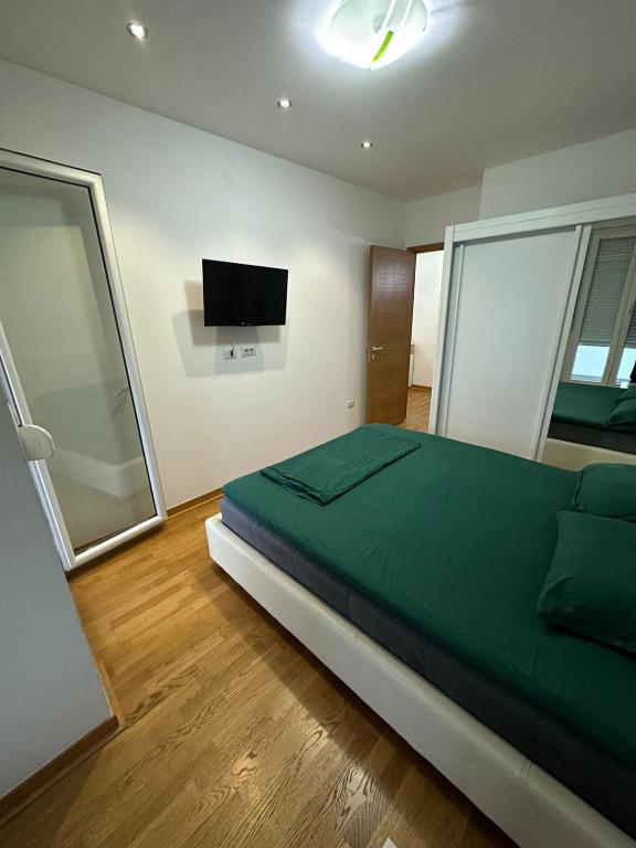 a bedroom with a green bed and a flat screen tv at Emina apartment City kvart in Kruševac