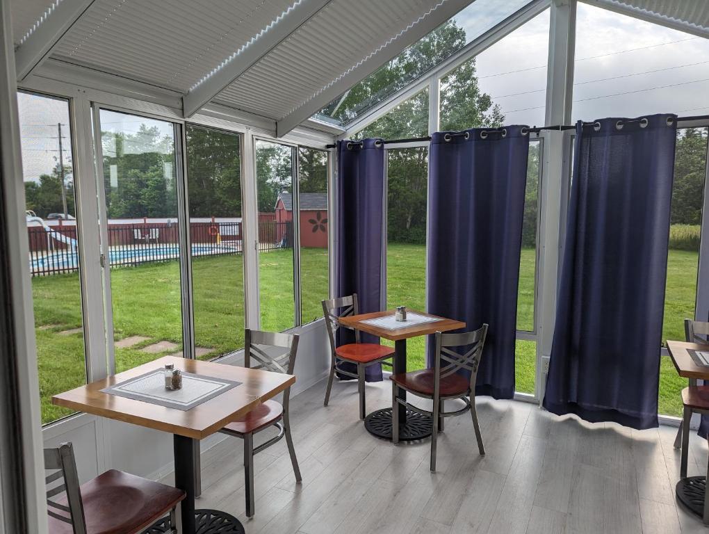 two tables and chairs in a room with windows at The Parrsboro Mansion Inn in Parrsboro