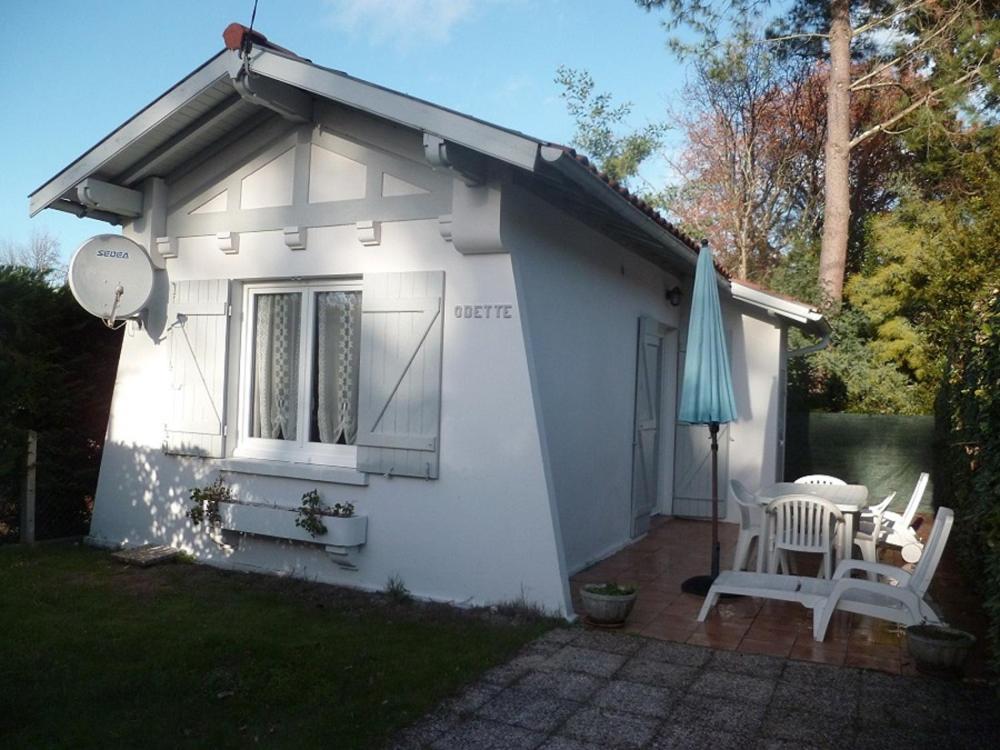 une petite maison blanche avec une table et un parasol dans l'établissement Petite villa calme à Arcachon, à Arcachon