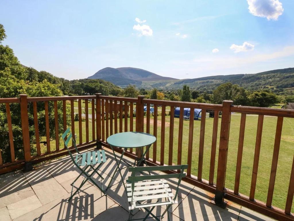 a table and a chair on a balcony with mountains at Ty Bach in Caernarfon