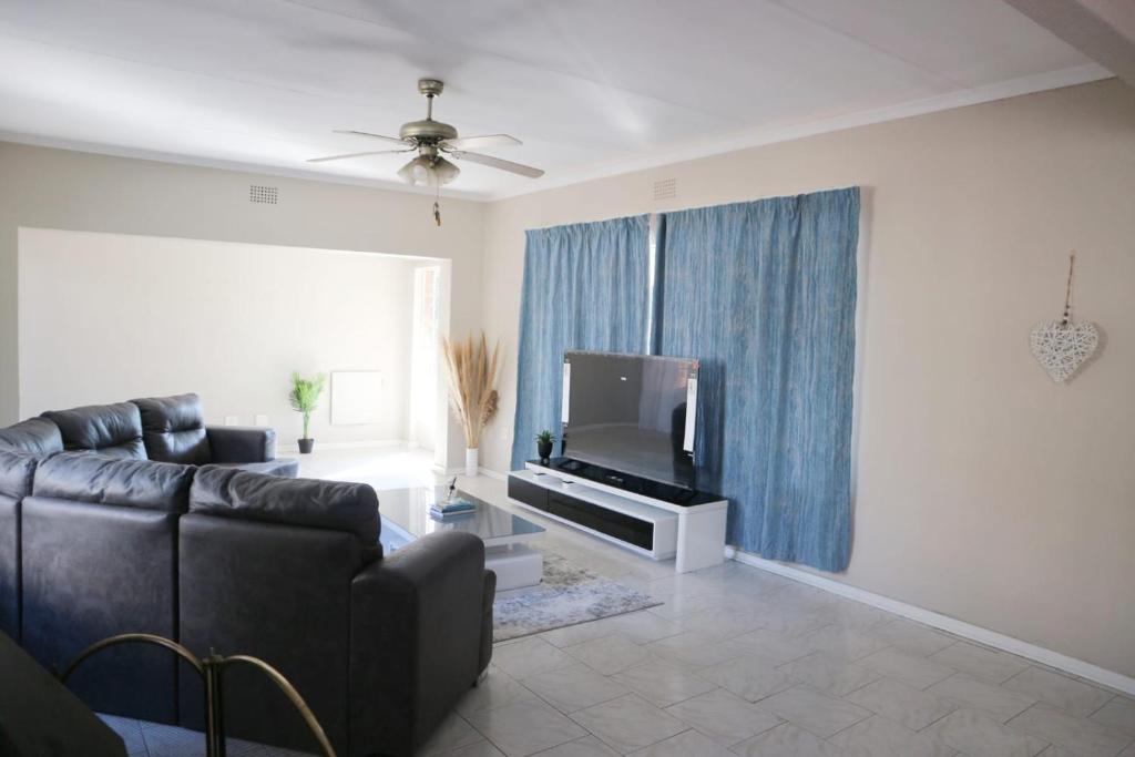 a living room with a couch and a flat screen tv at Israella Home in Boksburg