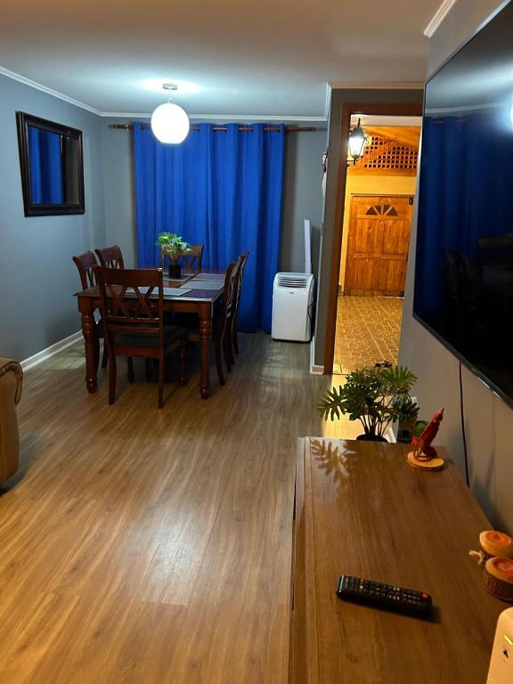 sala de estar con mesa y comedor con cortinas azules en casa, en La Chimba