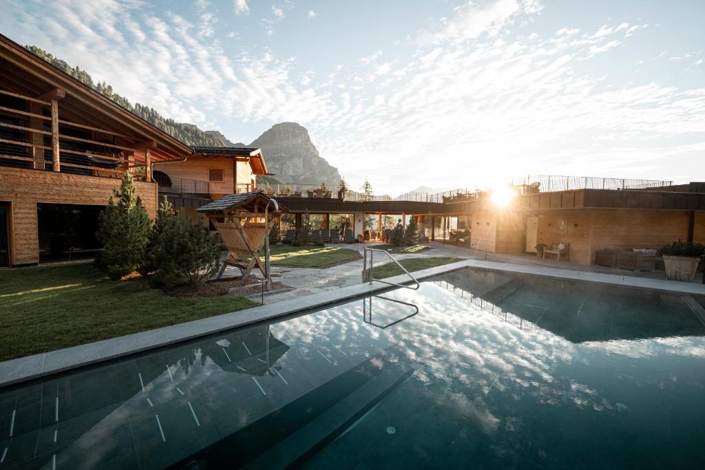 a house with a swimming pool with a mountain in the background at Kolfuschgerhof Mountain Resort in Colfosco