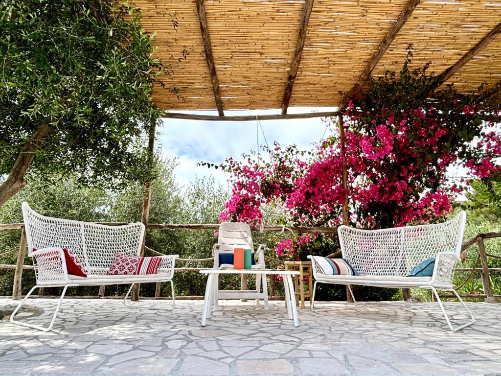a patio with three chairs and a table and flowers at Le petit By Gargà Residency in Peschici