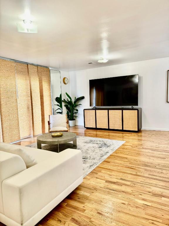 uma sala de estar com um sofá branco e uma televisão de ecrã plano em Stylish Evergreen Apartment By Newark Airport em Newark