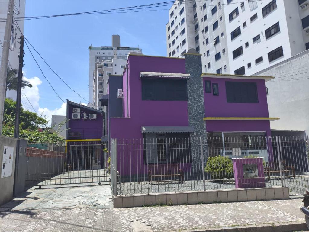 Pousada Casa da Maga - Vila Germânica في بلوميناو: مبنى أرجواني خلف سور في مدينة