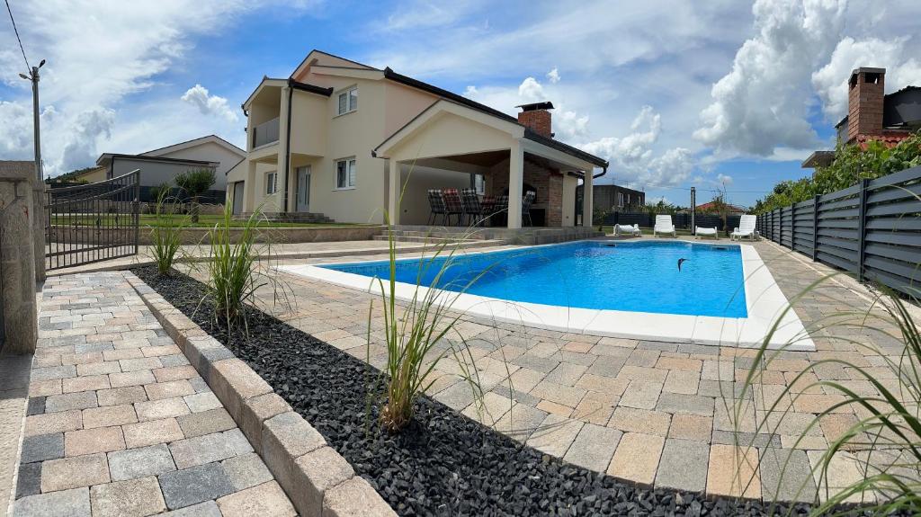 a swimming pool in front of a house at Guest House Ana Marija in Ljubuški