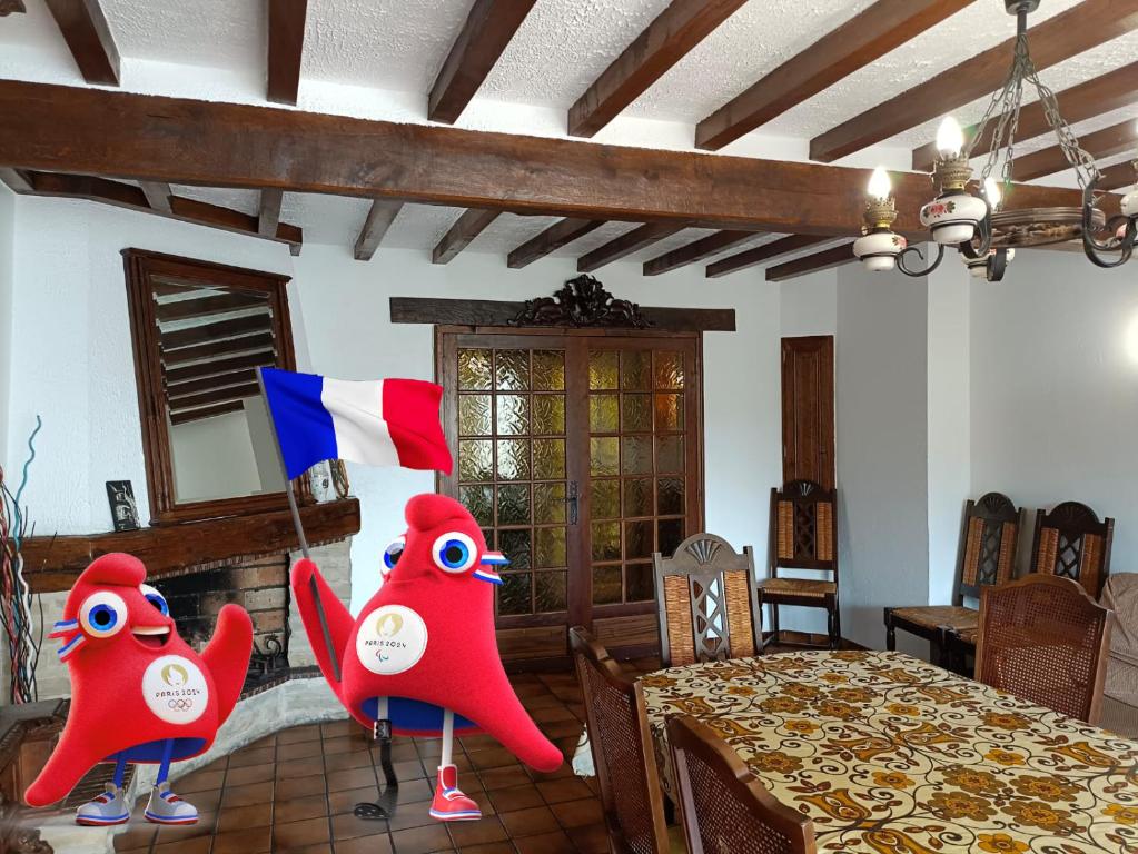 ein Esszimmer mit einem Tisch mit zwei roten Monstern in der Unterkunft Country house, 2024 Olympic Games, Pet Friendly in Romainville