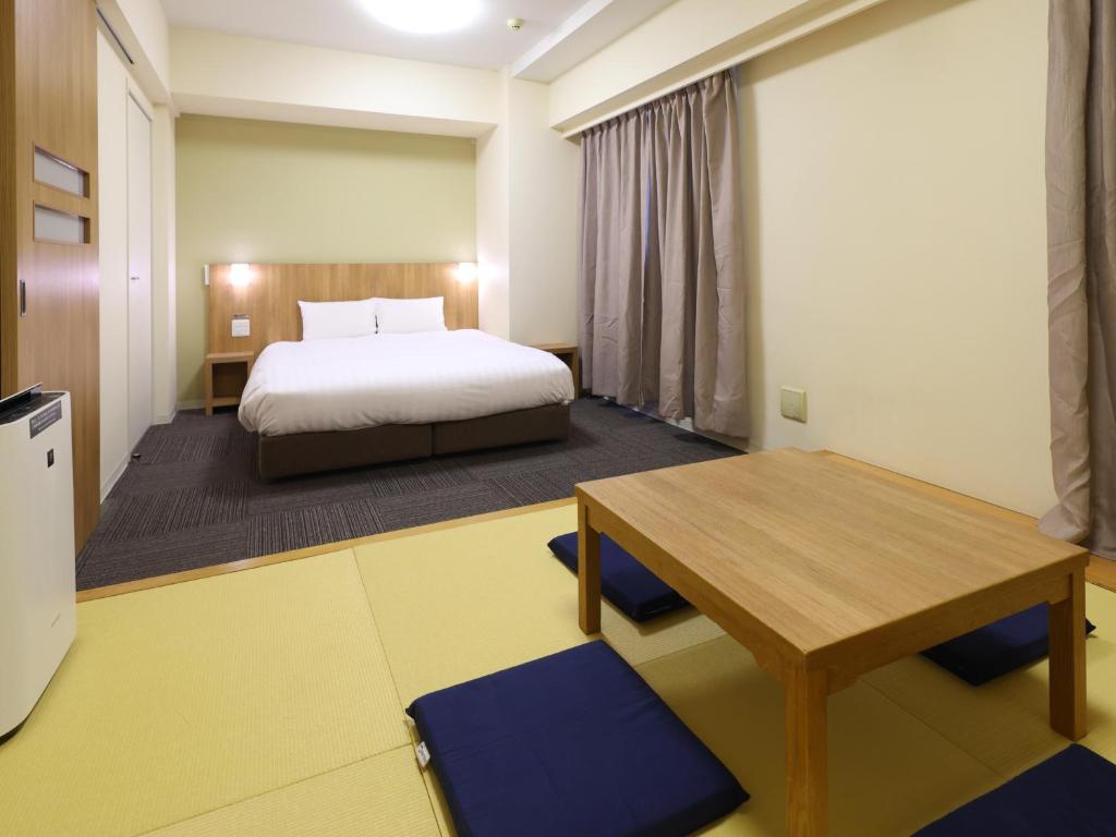1 dormitorio con cama, escritorio y mesa en Dormy Inn Express Mikawaanjo, en Anjomachi
