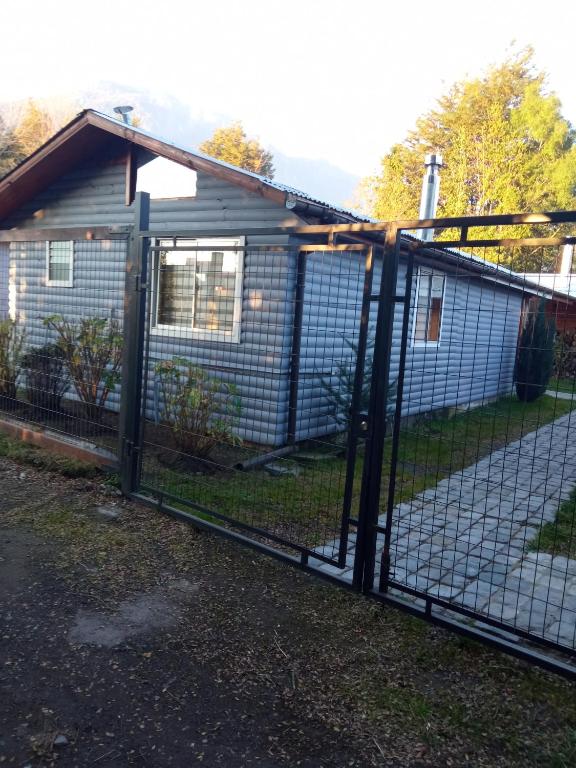a chain link fence with a gate in front of a house at Cabaña Gloria in Coñaripe