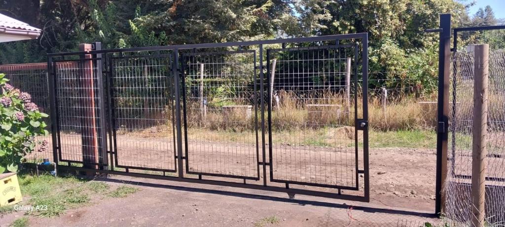 a metal gate with a fence in front of a field at Cabaña Gloria in Coñaripe