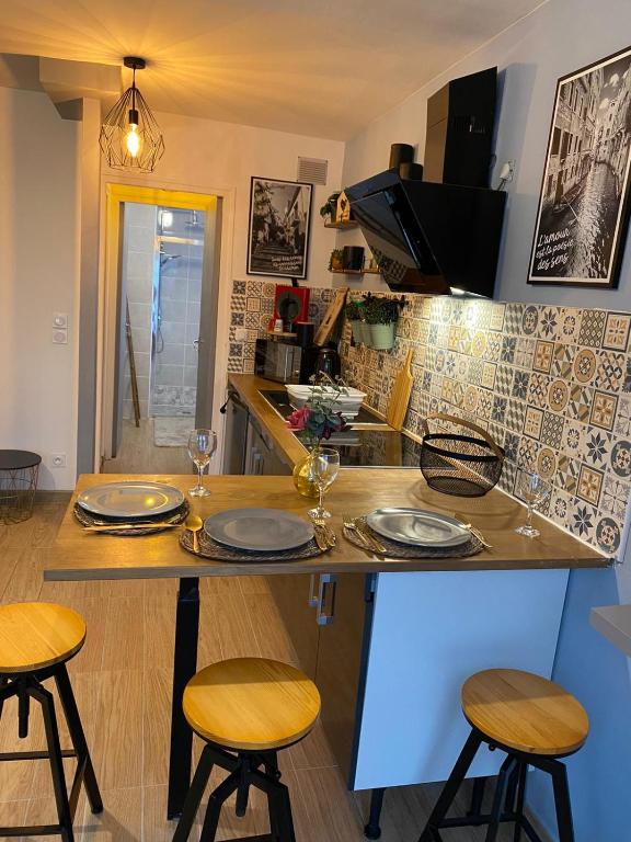 une cuisine avec un comptoir avec des tabourets et une table avec des assiettes dans l'établissement n3 jolie coin 15min des plage, à Hérouville-Saint-Clair