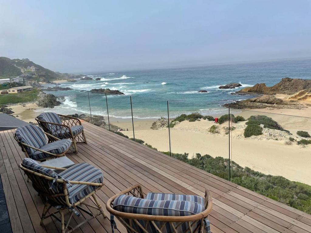 a group of chairs sitting on a deck looking at the beach at SitenKyk beachfront self catering accommodation in Eersterivierstrand