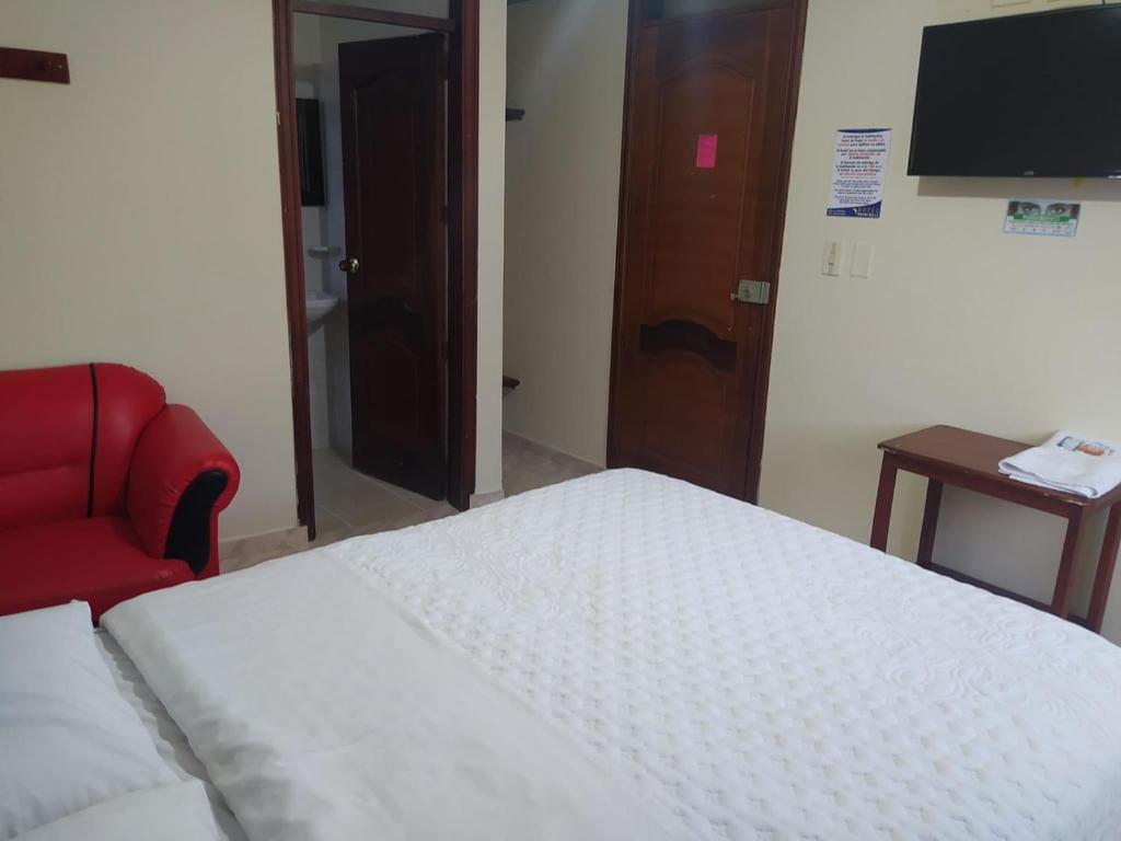 um quarto com uma cama e uma cadeira vermelha em Hotel Noche Bella em Ipiales