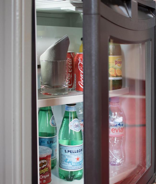 a refrigerator filled with bottles of soda and drinks at Hotel America in Cannes