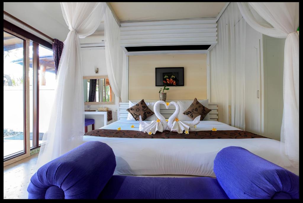 a bedroom with a large white bed with curtains at Private Pool Classic Villa in Kuta