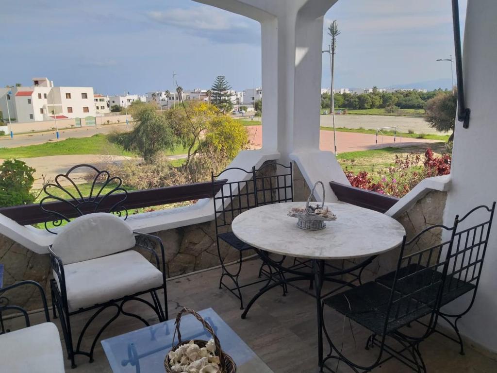 a balcony with tables and chairs and a view of the street at Appartement moderne à 5 min de la plage in Cabo Negro