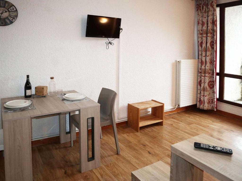 une salle à manger avec une table et une télévision murale dans l'établissement Studio cosy pour 2 en plein centre, Les Orres 1650 - FR-1-322-612, aux Orres