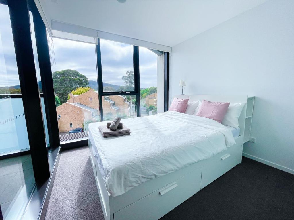 a bedroom with a white bed and a large window at The Metropol 2BR Apt, In the heart of CBD 2b1b1c, Free parking, Wi-Fi in Canberra