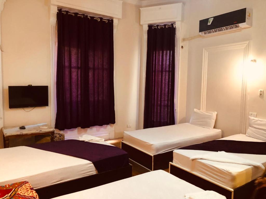 a hotel room with three beds and a television at OH! Cairo Pharaoh Hostel in Cairo