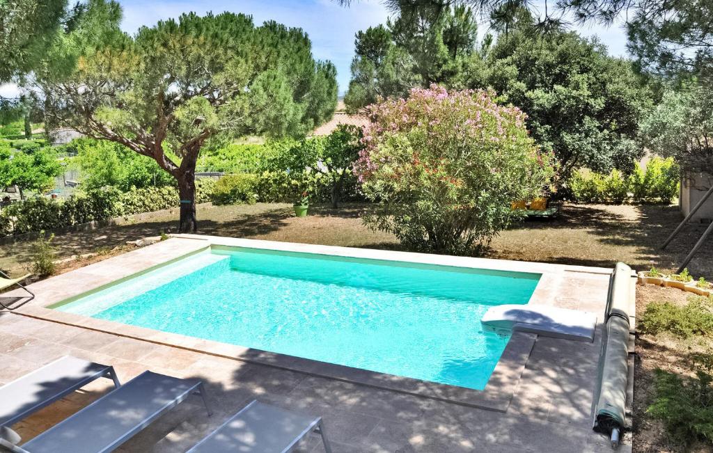 - une piscine dans une cour avec des chaises et des arbres dans l'établissement La Villa Des Pins, à Rochefort-du-Gard