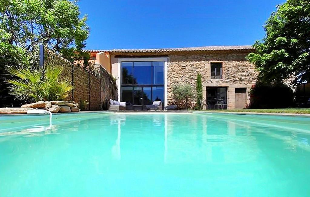 una gran piscina frente a una casa en Le Mas Moreau en Sainte-Cécile-les-Vignes