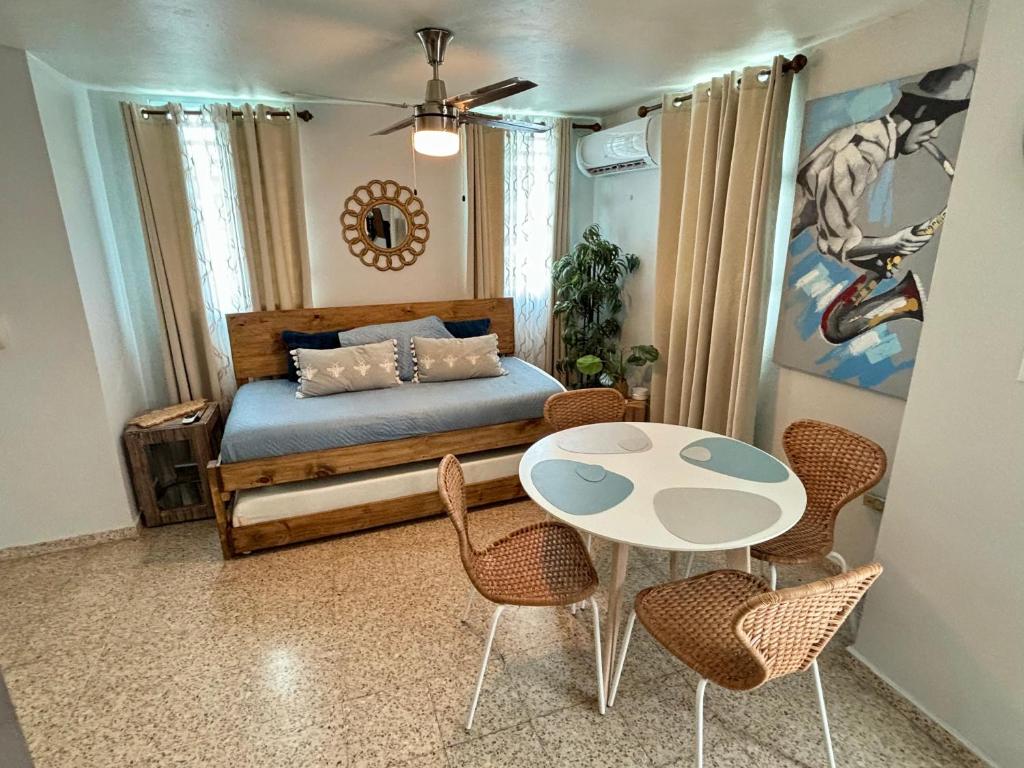 1 dormitorio con 1 cama, mesa y sillas en Bee Inn Puerto Rico Charming Urban Apartment in San Juan en San Juan