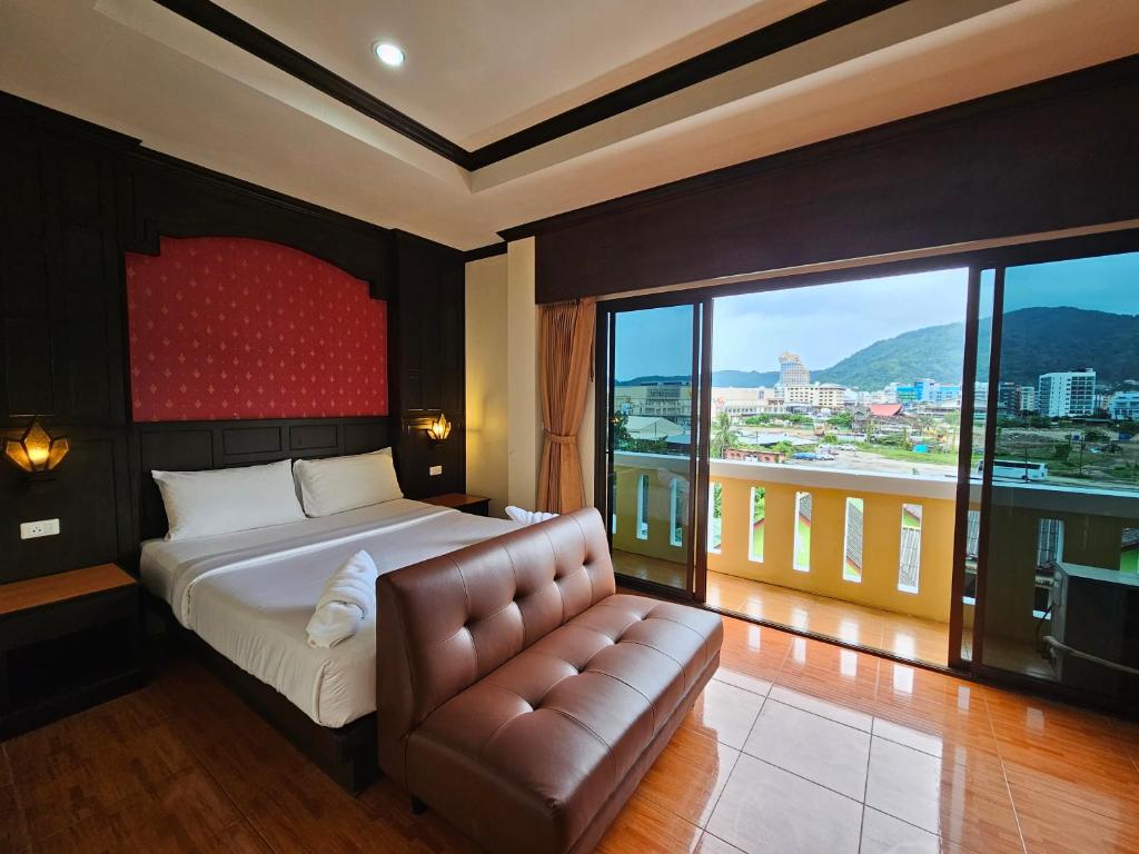 a bedroom with a bed and a couch and a large window at Nanai 2 Residence Patong Phuket in Patong Beach