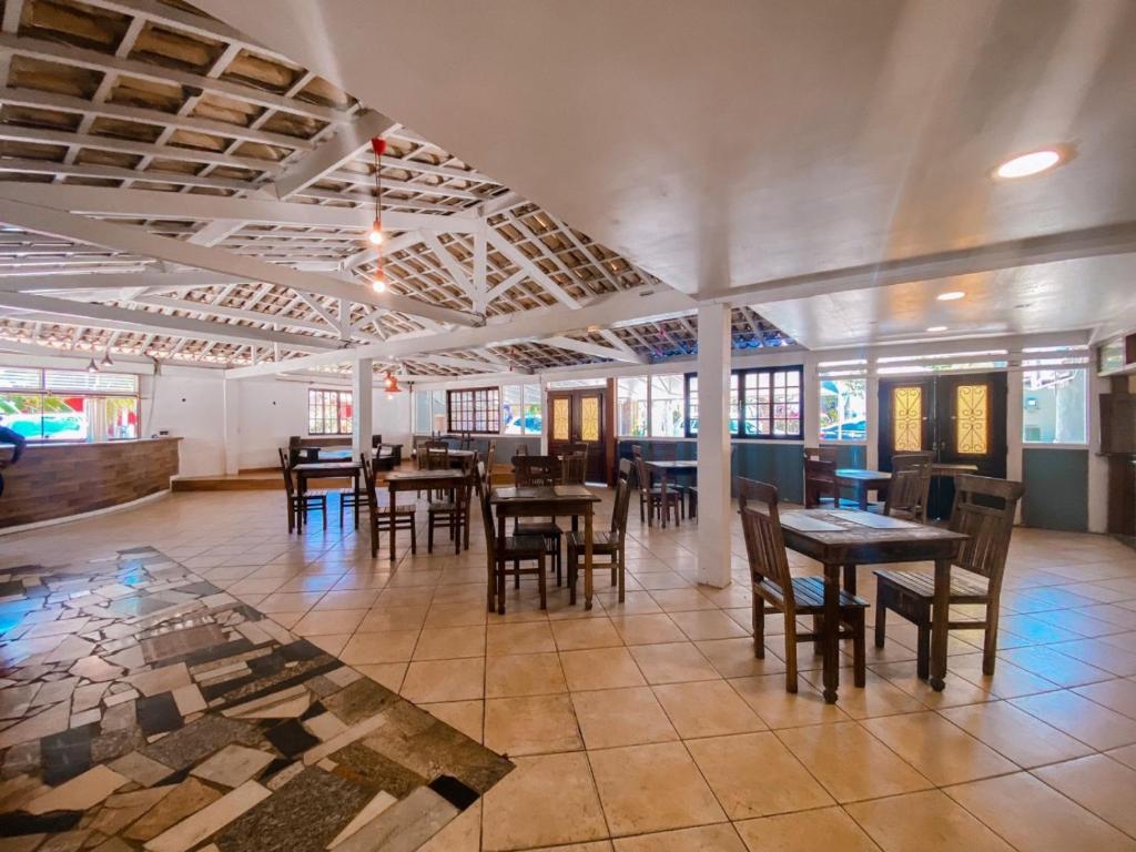 uma sala de jantar com mesas, cadeiras e janelas em Super Flats Geribá em Búzios