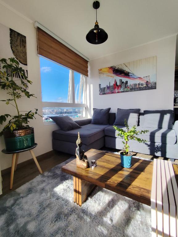 ein Wohnzimmer mit einem blauen Sofa und einem Tisch in der Unterkunft Espectacular departamento con vista a Laguna in Concepción