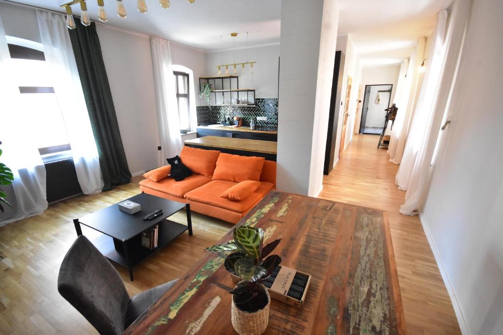 シュフィドニツァにあるApartamenty Basztowaのリビングルーム(オレンジ色のソファ、テーブル付)