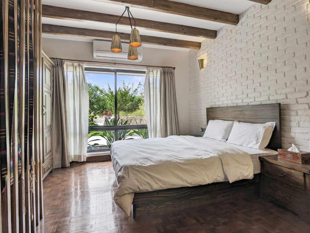 een slaapkamer met een groot bed en een groot raam bij Uma Residency- Drongpa Suites in Kathmandu