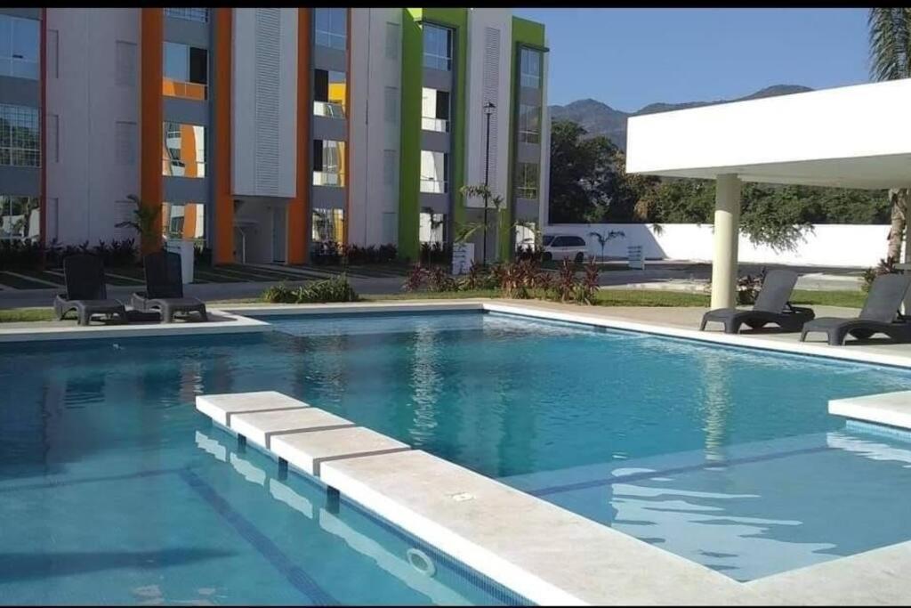 ein Pool mit zwei Stühlen und ein Gebäude in der Unterkunft Departamento hermoso y cómodo in La Sabana