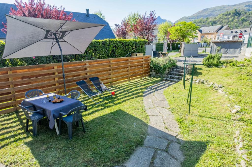 - une table et des chaises avec un parasol dans la cour dans l'établissement Appartement « Villa Josy » cosy à Argelès-Gazost avec jardin, à Argelès-Gazost