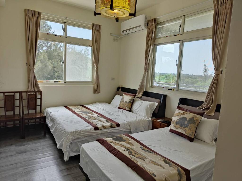 2 camas en una habitación con 2 ventanas en 金門馨紫晶民宿, en Jinning