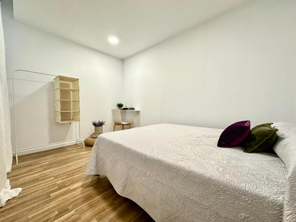 a white bedroom with a bed and a wooden floor at The Valencia Stop in Valencia