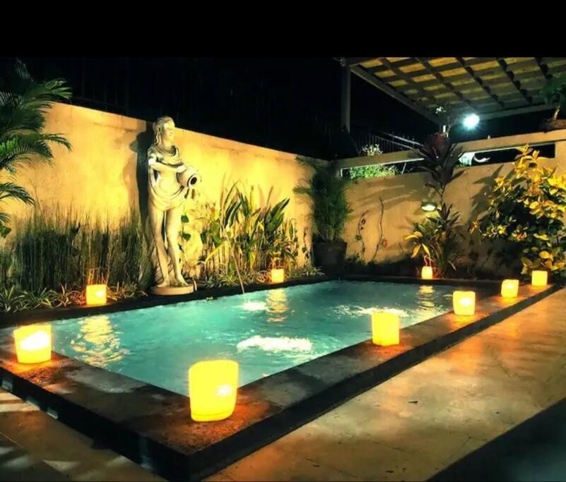 a pool with candles and a statue in a building at Villa Ariani Keselurahan, 3 BR in Keramas