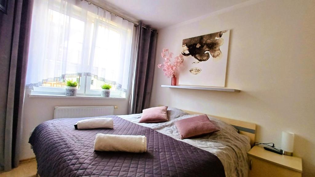 a bedroom with a bed with pink pillows and a window at Apartament Orange Piastowska in Ostróda