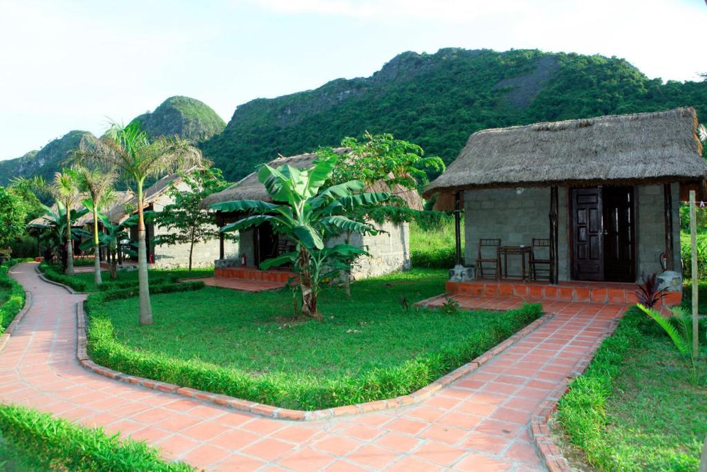 une petite maison avec un toit en gazon et une passerelle en briques dans l'établissement Whisper Nature Bungalow & Resort, à Cat Ba