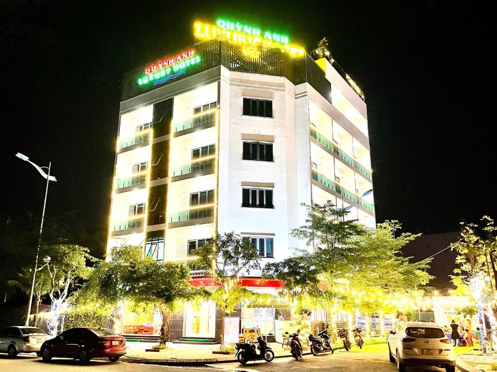 a hotel building with cars parked in front of it at night at Quỳnh Anh Luxury Hotel Sầm Sơn in Sầm Sơn