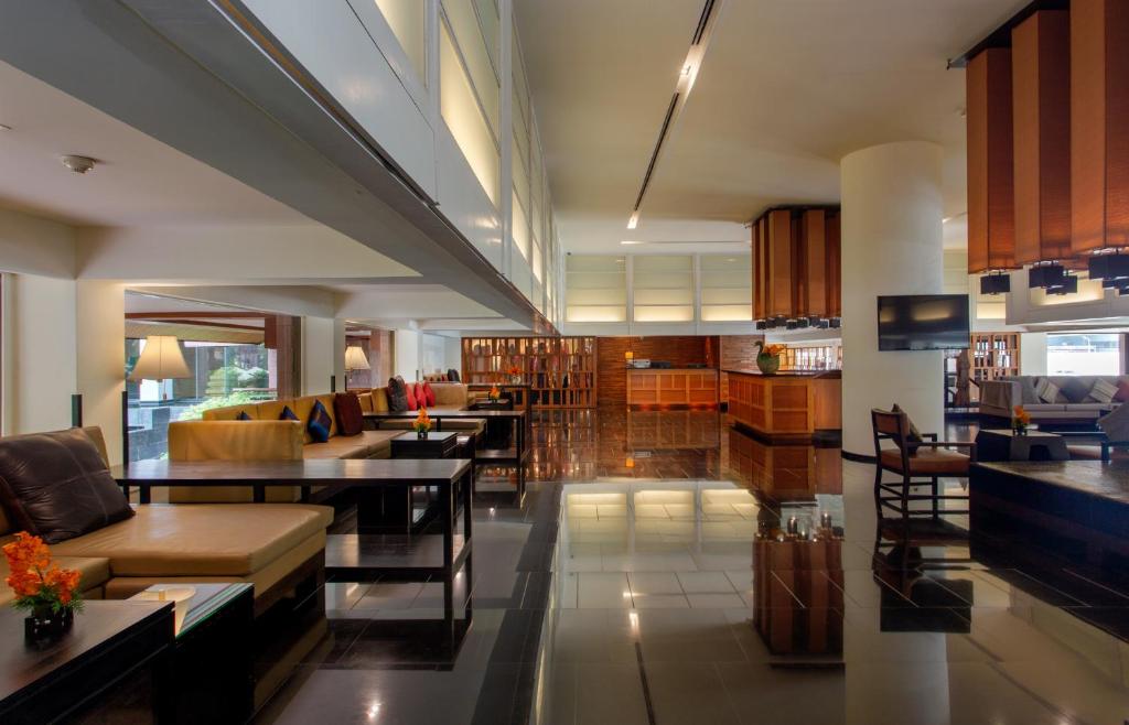 A polished lobby lounge with sofas, low tables, bookshelves and a reception area.