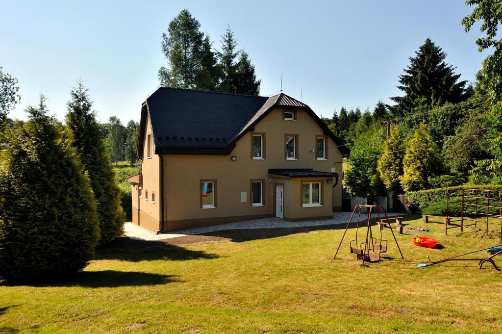 une petite maison avec une aire de jeux dans la cour dans l'établissement Vila Vlčí Hora, à Krásná Lípa