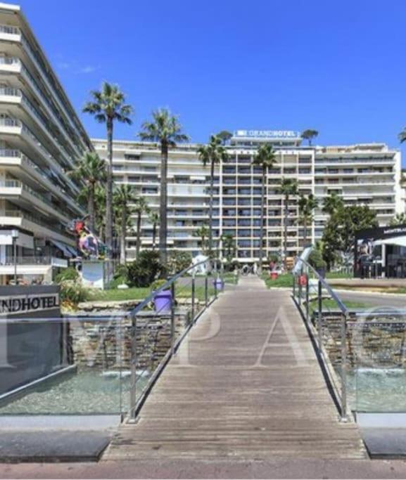 une promenade en bois devant un grand bâtiment dans l'établissement Grand Hotel 2 chambres 2 sdb - GH, à Cannes