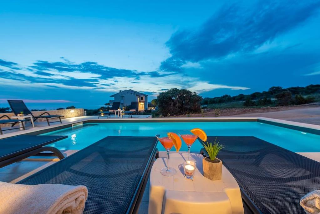 ein Pool mit einem Tisch und Stühlen daneben in der Unterkunft Sunset mood modern ap with a pool for 6 in Novalja