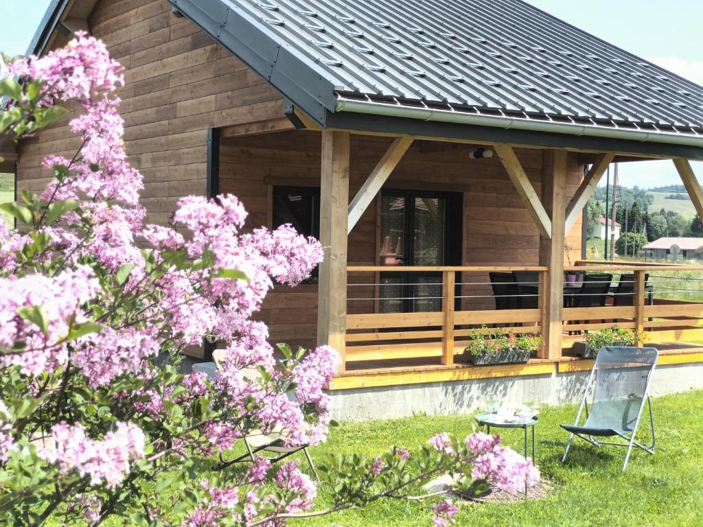 a wooden cabin with pink flowers in front of it at L étincelle du Manon in Lajoux