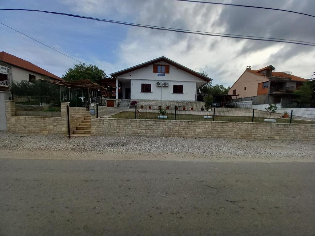 une maison blanche avec une clôture devant elle dans l'établissement Appartement Nicole BENKOVAC, à Benkovac