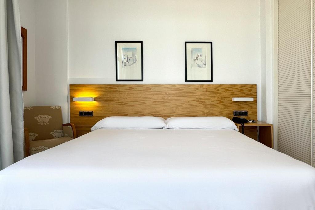 a bedroom with a large white bed with three pictures on the wall at Hotel Don Ignacio in San José